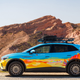 A VW ID.4 with a vibrant blue and orange livery parked in the desert
